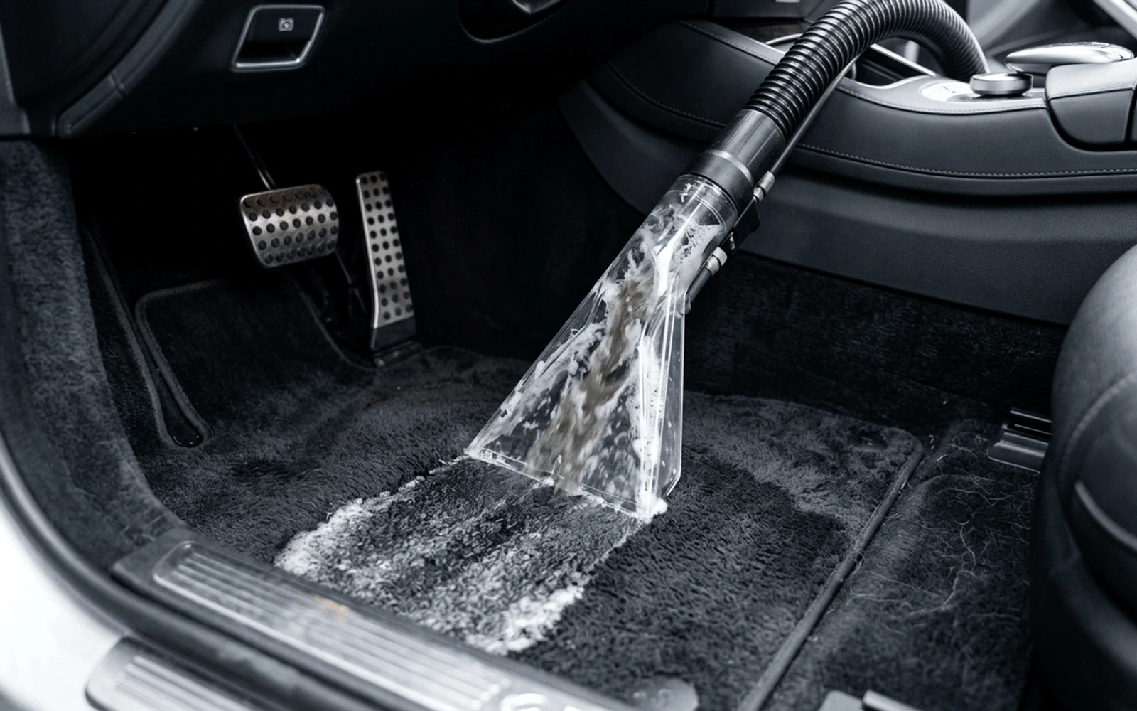 Claw vacuum nozzle extracting deeply embedded sand from automotive floor carpet